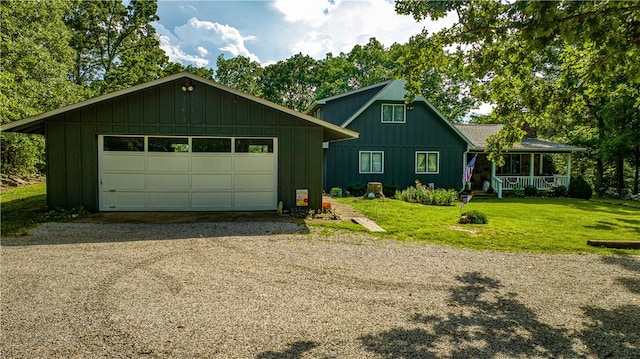 view of front of property featuring a garage, a porch, a front yard, and an outbuilding