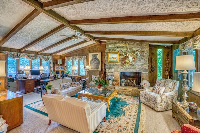 living room featuring lofted ceiling with beams, carpet, a fireplace, wooden walls, and ceiling fan