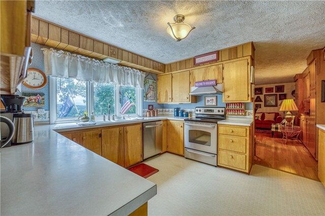 kitchen featuring stainless steel appliances, a textured ceiling, and light wood-type flooring