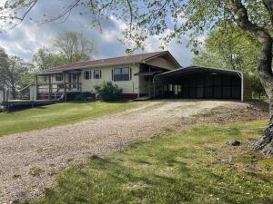 view of front facade featuring driveway, a carport, and a front yard