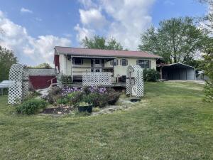 rear view of house with a lawn and a carport