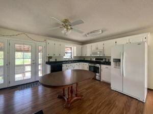 kitchen with white appliances, french doors, dark hardwood / wood-style flooring, white cabinetry, and ceiling fan