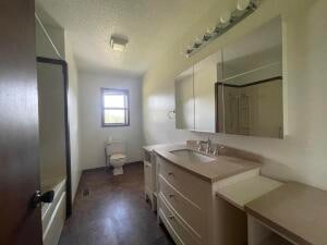 bathroom with a textured ceiling, a shower, vanity, and toilet