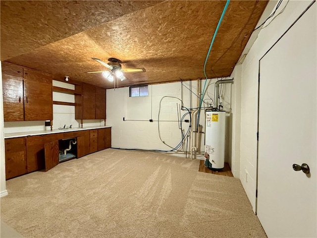 basement with sink, water heater, ceiling fan, and light colored carpet