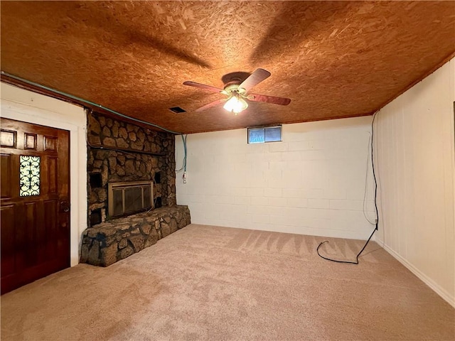 interior space with carpet flooring, ceiling fan, and a stone fireplace