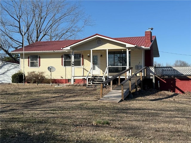 view of front facade featuring covered porch, metal roof, and a chimney