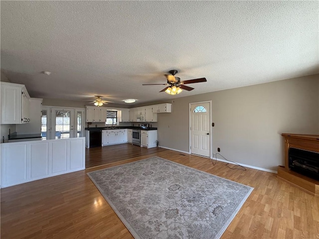 kitchen with dark countertops, stainless steel range with electric stovetop, white cabinets, and wood finished floors