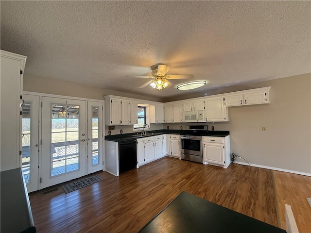 kitchen with dark wood-style floors, stainless steel electric stove, dark countertops, white microwave, and dishwasher