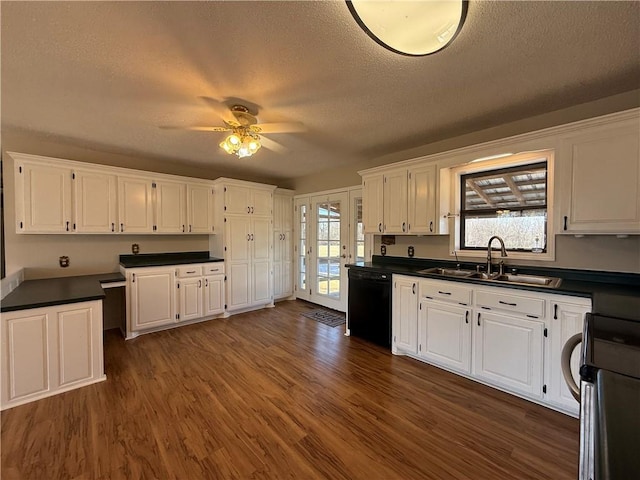 kitchen featuring dark wood-style flooring, a sink, white cabinets, black dishwasher, and range