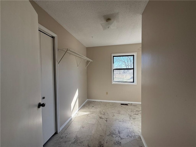 laundry area with a textured ceiling, marble finish floor, and baseboards