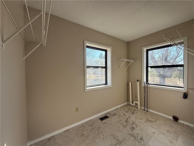 washroom with laundry area, visible vents, marble finish floor, and a healthy amount of sunlight