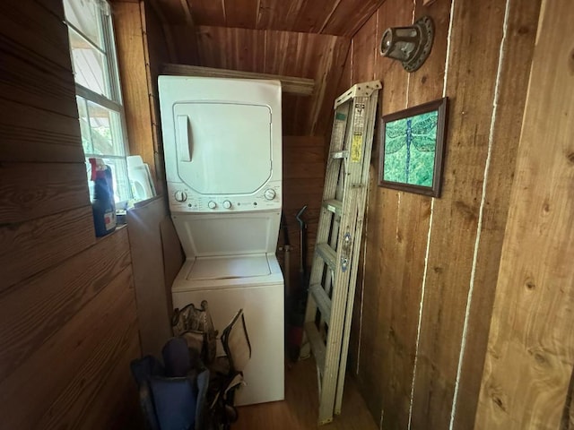 clothes washing area featuring wood walls, stacked washing maching and dryer, and wood ceiling