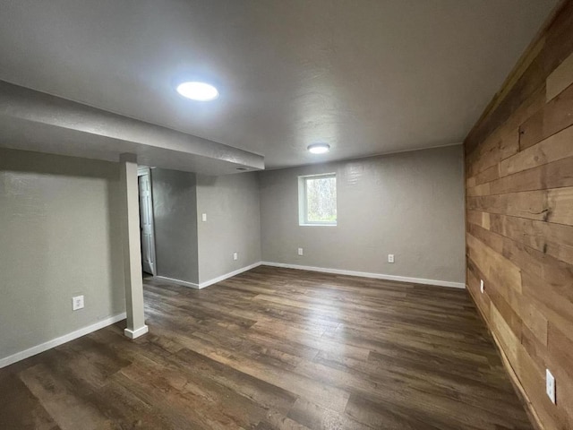 basement featuring dark hardwood / wood-style flooring and wooden walls