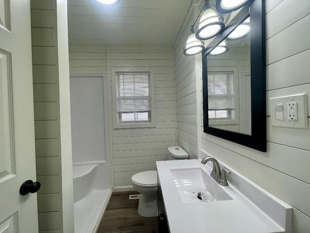 bathroom featuring toilet, vanity, wood-type flooring, and wooden walls