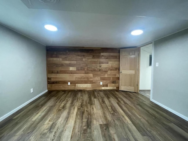 unfurnished room featuring dark wood-type flooring and wood walls