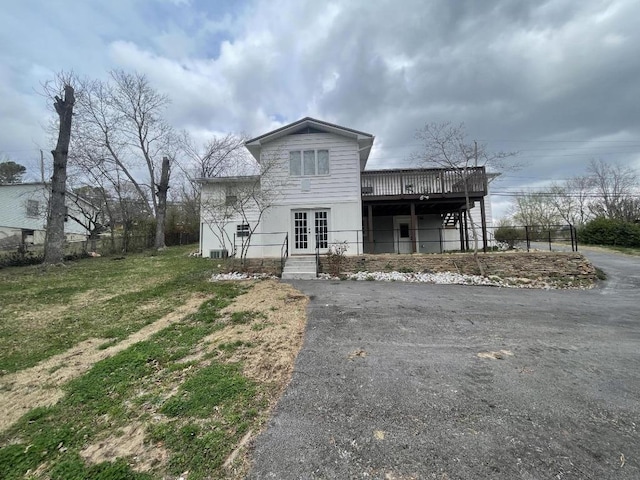 back of house with a wooden deck, a lawn, and french doors