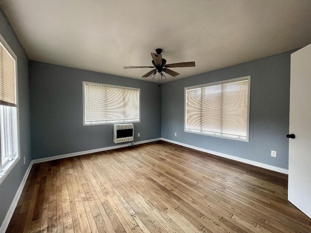 spare room with heating unit, wood-type flooring, and ceiling fan