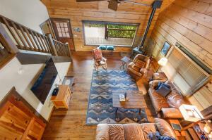 living room with stairway, a ceiling fan, wooden walls, and wood finished floors