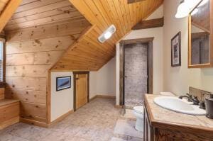 bathroom featuring vaulted ceiling, wooden ceiling, vanity, and baseboards