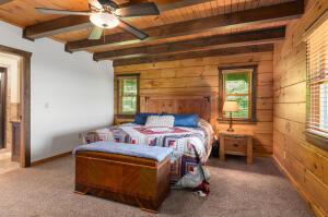 bedroom with carpet floors, wood ceiling, beam ceiling, and wooden walls