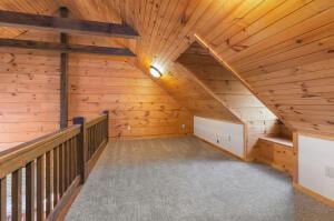 additional living space with vaulted ceiling, wooden ceiling, and wooden walls