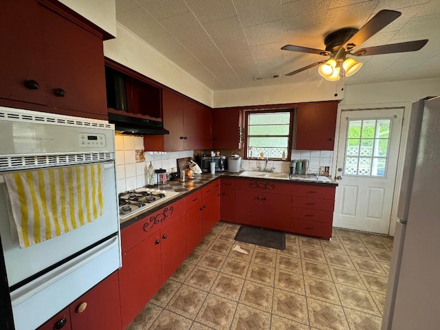 kitchen with backsplash, sink, light tile patterned floors, white appliances, and ceiling fan