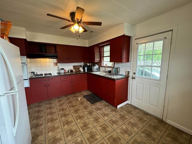 kitchen featuring stainless steel gas cooktop, decorative backsplash, sink, ceiling fan, and white refrigerator