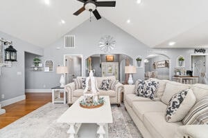 living room featuring high vaulted ceiling, ceiling fan, and light wood-type flooring