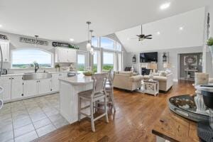 kitchen with sink, light hardwood / wood-style flooring, vaulted ceiling, ceiling fan, and white cabinetry