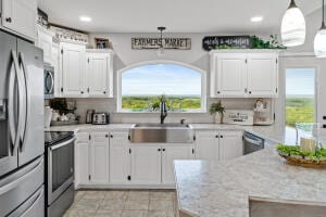 kitchen featuring sink, appliances with stainless steel finishes, a healthy amount of sunlight, and white cabinets