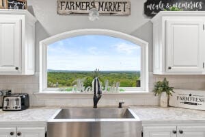 kitchen with sink, tasteful backsplash, white cabinets, and a wealth of natural light