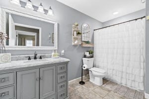 bathroom featuring tile patterned flooring, a shower with shower curtain, vanity, and toilet