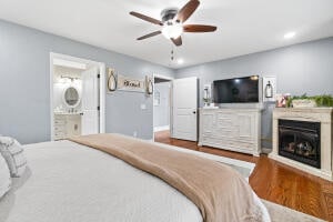 bedroom with hardwood / wood-style floors, ceiling fan, and ensuite bath