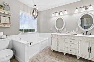 bathroom featuring an inviting chandelier, a bath, vanity, tile patterned floors, and toilet