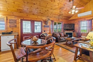 dining area featuring wooden walls, vaulted ceiling, and a healthy amount of sunlight