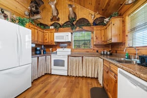 kitchen featuring sink, wood walls, light hardwood / wood-style floors, and white appliances