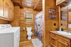 bathroom with wood walls, hardwood / wood-style floors, vanity, beamed ceiling, and toilet