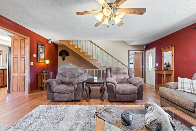 living room featuring ceiling fan, a textured ceiling, and wood-type flooring