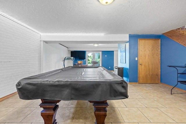 playroom featuring a textured ceiling, pool table, and light tile patterned floors