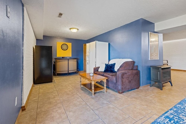 tiled living room featuring a textured ceiling and a wood stove