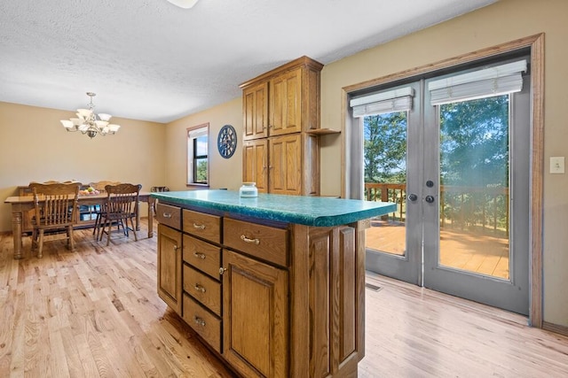 kitchen featuring light hardwood / wood-style flooring, a chandelier, a kitchen island, french doors, and decorative light fixtures