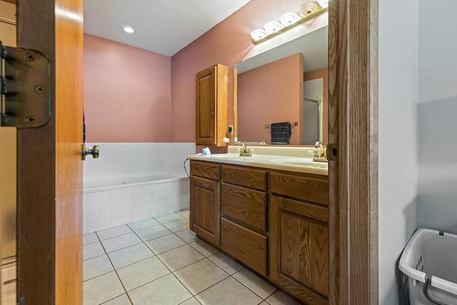 bathroom featuring tiled bath, tile patterned floors, a textured ceiling, and vanity