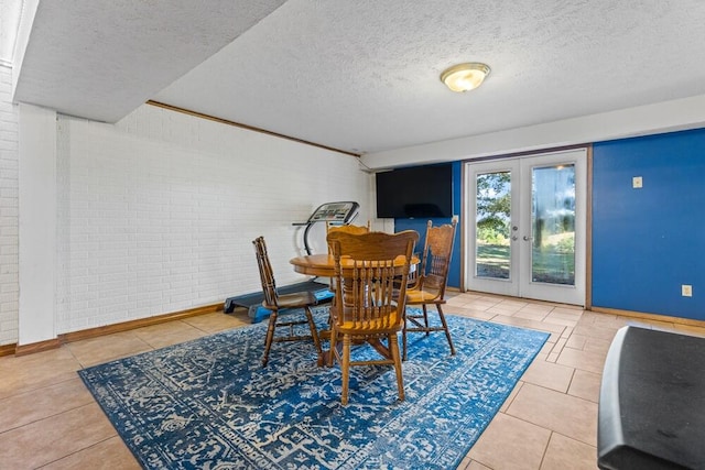 tiled dining space featuring french doors, brick wall, and a textured ceiling