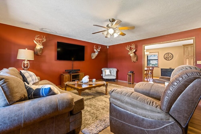 living room with a textured ceiling, ceiling fan, and hardwood / wood-style floors