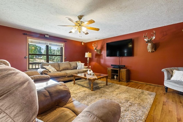 living room featuring ceiling fan, wood-type flooring, and a textured ceiling