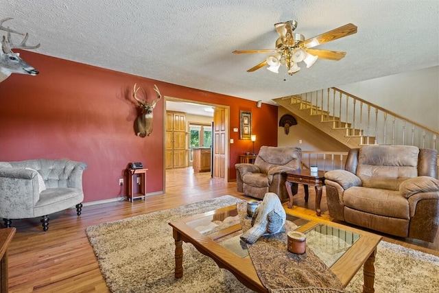 living room with ceiling fan, wood-type flooring, and a textured ceiling