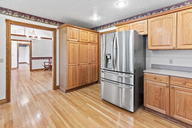 kitchen featuring stainless steel fridge, a notable chandelier, light hardwood / wood-style flooring, and a textured ceiling