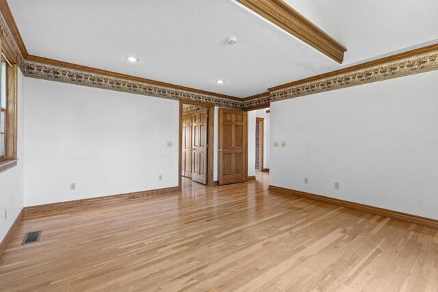 empty room with light hardwood / wood-style floors and ornamental molding