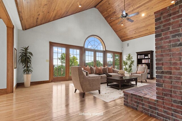 living room with high vaulted ceiling, light hardwood / wood-style floors, wooden ceiling, ceiling fan, and brick wall