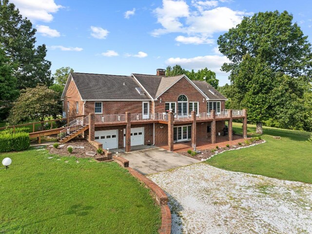 back of property with a deck, a yard, and a garage